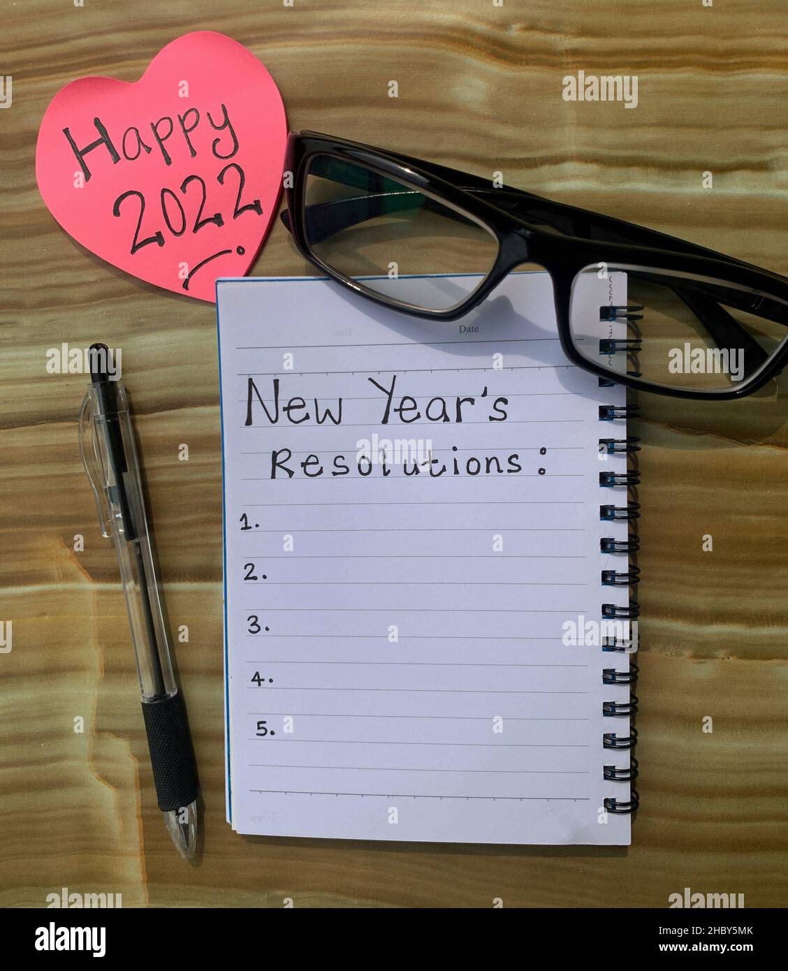 Auflösung für das neue Jahr 2022 auf einem Notizblock mit Stift, Brille und Haftnotiz-Hintergrund geschrieben Stockfoto