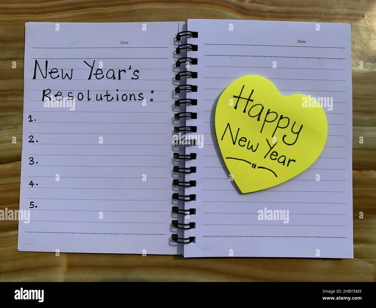 Schöne Wünsche auf Haftnotizen mit einem auf einem Notizblock geschriebenen Vorsatz für das neue Jahr. Stockfoto