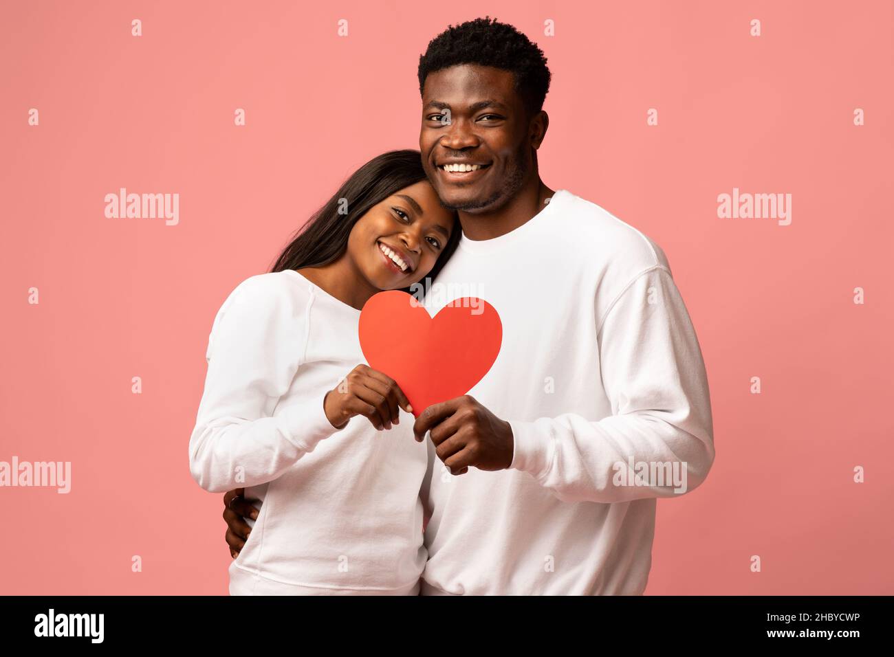 Glückliches afroamerikanisches Paar, das Liebe feiert, rosa Hintergrund Stockfoto