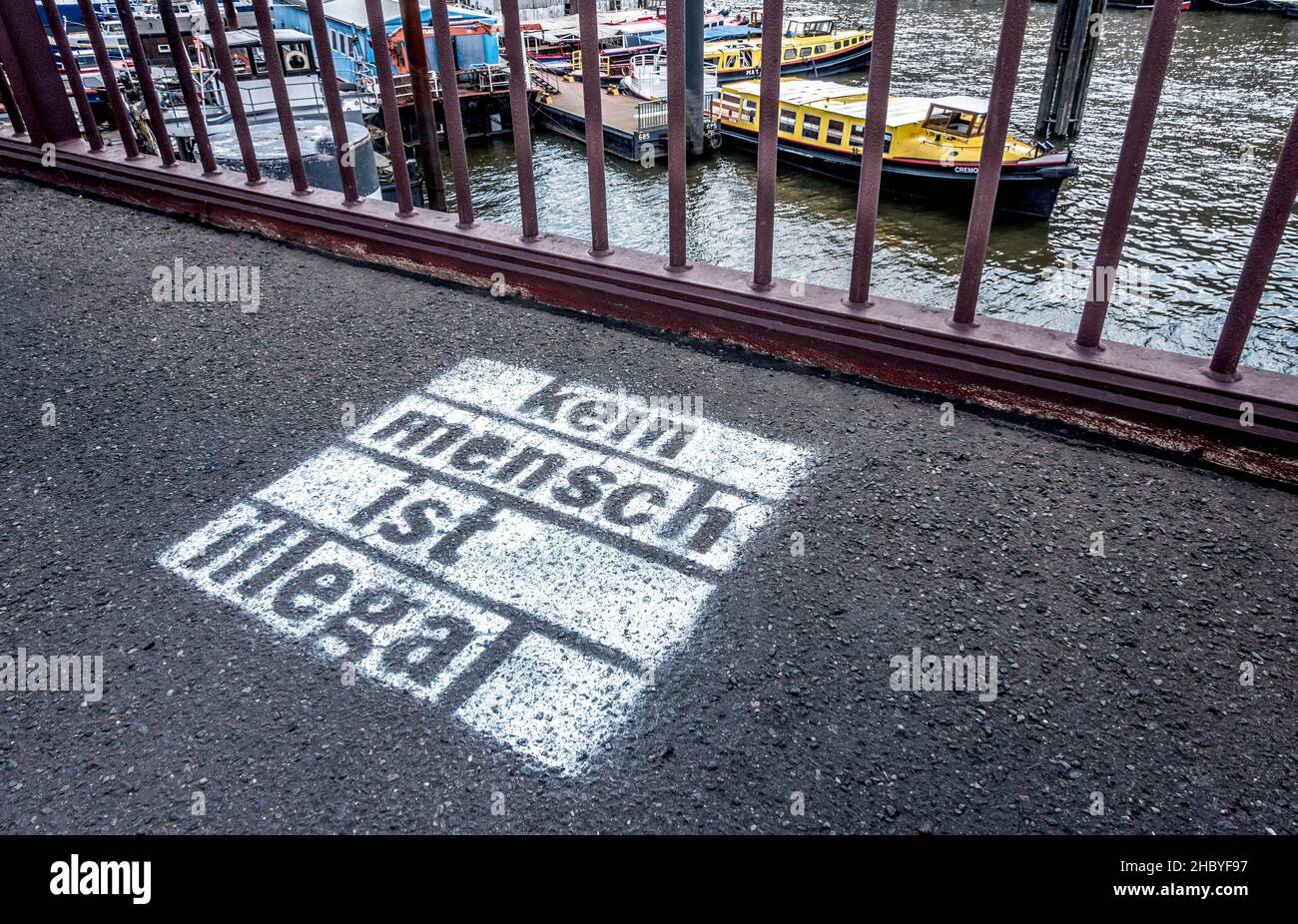 Slogan - kein Mensch ist illegal - auf dem Asphalt am Hamburger Hafen, Hamburg, Deutschland Stockfoto