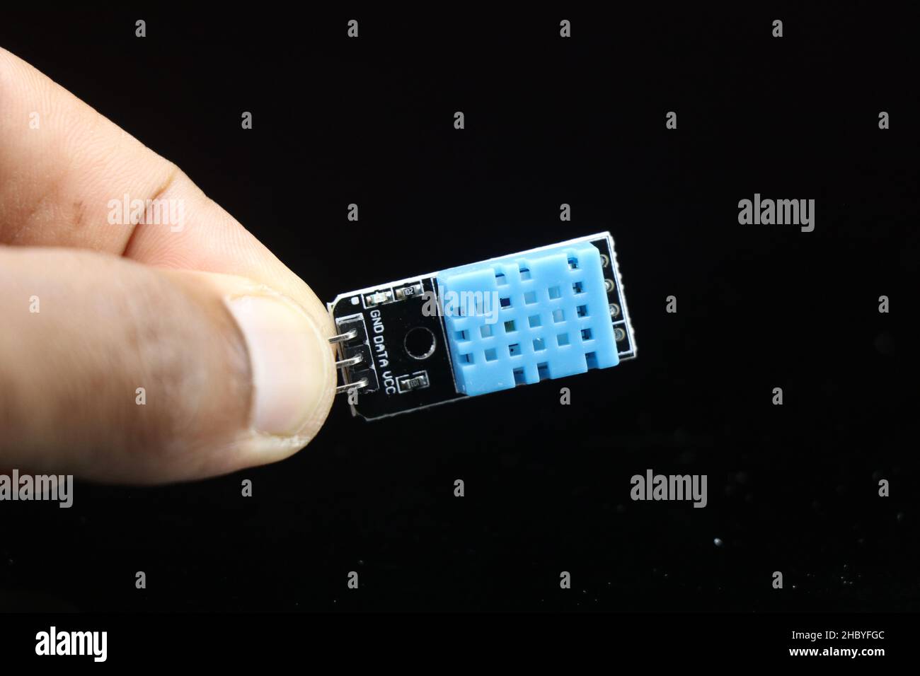 Temperatur- und Feuchtigkeitssensormodul oder DHT11-Platine in der Hand gehalten, isoliert auf schwarzem Hintergrund Stockfoto