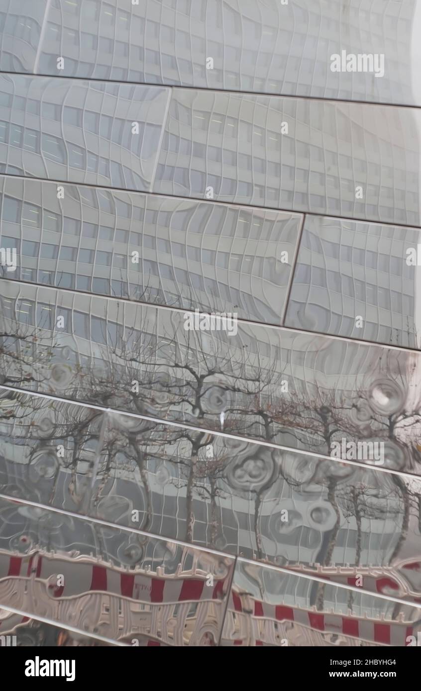 Verzerrte Spiegelung eines Wolkenkratzers und eines Umzäunens der Baustelle, Stadtbild, das wirbelhaft abstrakte Formen formt Stockfoto