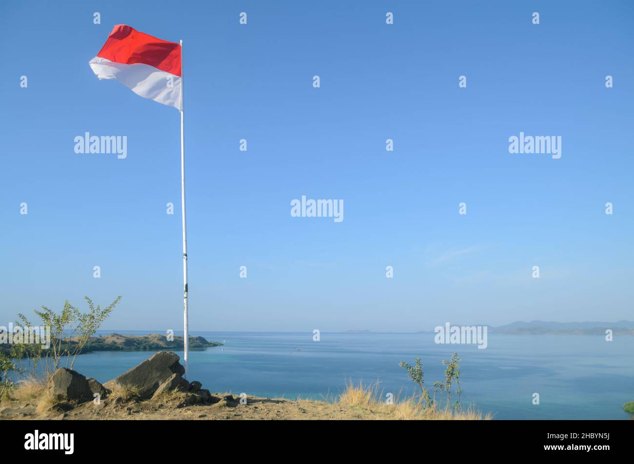 Indonesia National Flag mit klarem blauen Himmel und Meer im Hintergrund Stockfoto