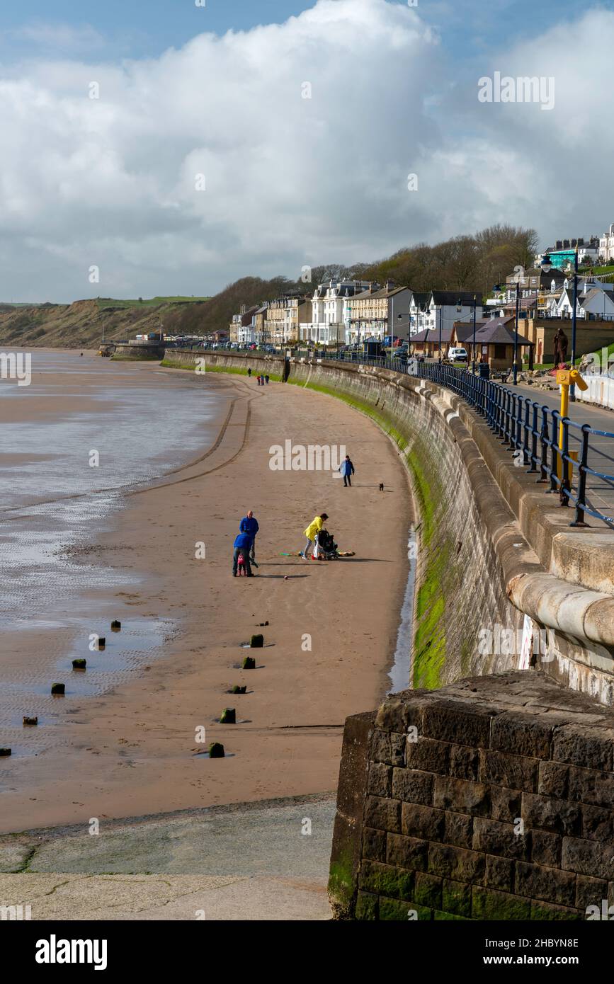 Die Leute genießen einen Spaziergang am Strand von Filey Stockfoto