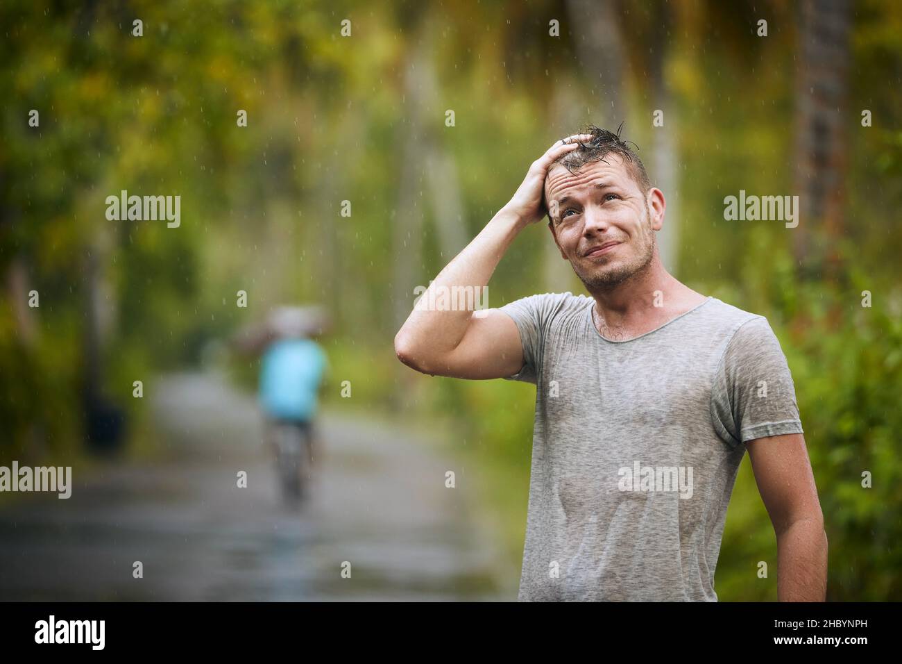 Porträt eines nassen jungen Mannes, der starken Regen in der Natur genießt. Stockfoto
