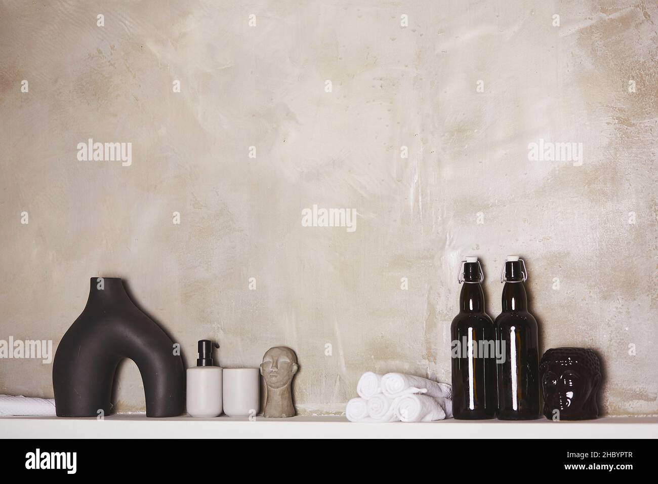 Bad-Accessoires für Spa-Verfahren. Handtuch, Flaschen, Shampoo und Buddhismus Figuren Dekorationen auf Beton Hintergrund. Flaschen nachmachen. Skandinavische Innenausstattung. Gemütliches Zuhause Konzept. Speicherplatz kopieren. Stockfoto