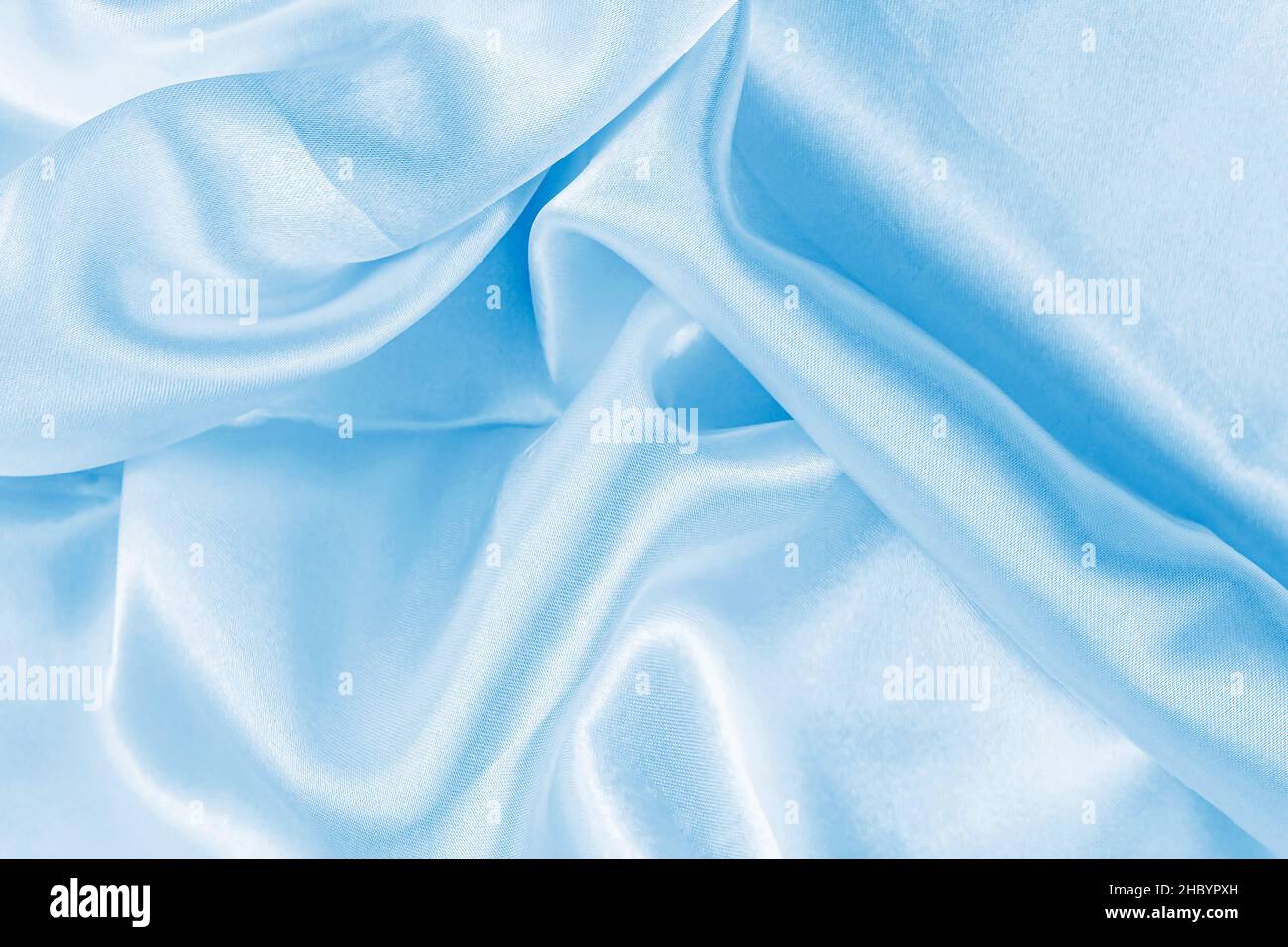 Hellblaues Seidengewelltes Textilmuster als glatter strukturierter Hintergrund. Himmelfarbene Vorhänge aus weichem Satin-Stoff. Stockfoto