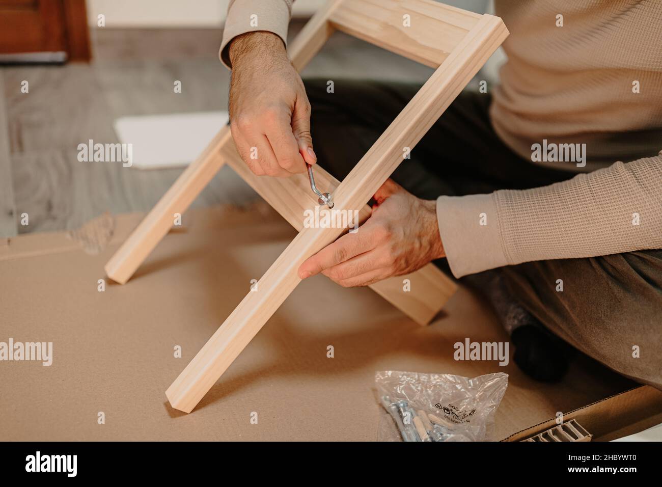 Ein erfahrener Mann montiert zu Hause Holzmöbel mit einem Sechskantschlüssel Stockfoto