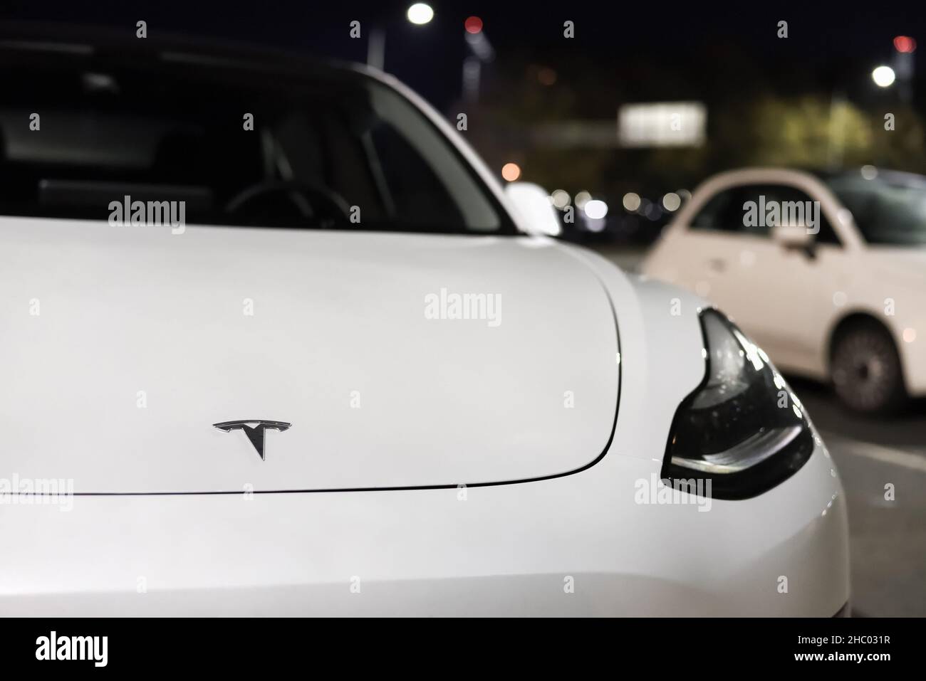 Weißes Elektroauto der Firma Tesla Motors. Tesla-Firmenlogo auf der vorderen Motorhaube des Elektroautos: Riga, Lettland - 22. September 2021. Stockfoto