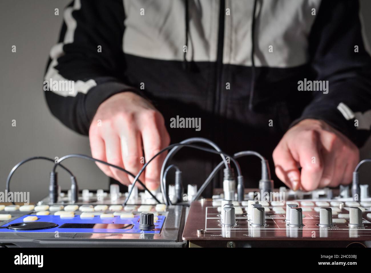 Synthesizer steuert Knöpfe vor dem Hintergrund der verschwommenen Hände des Musikers, während er elektronische Musik erzeugt Stockfoto