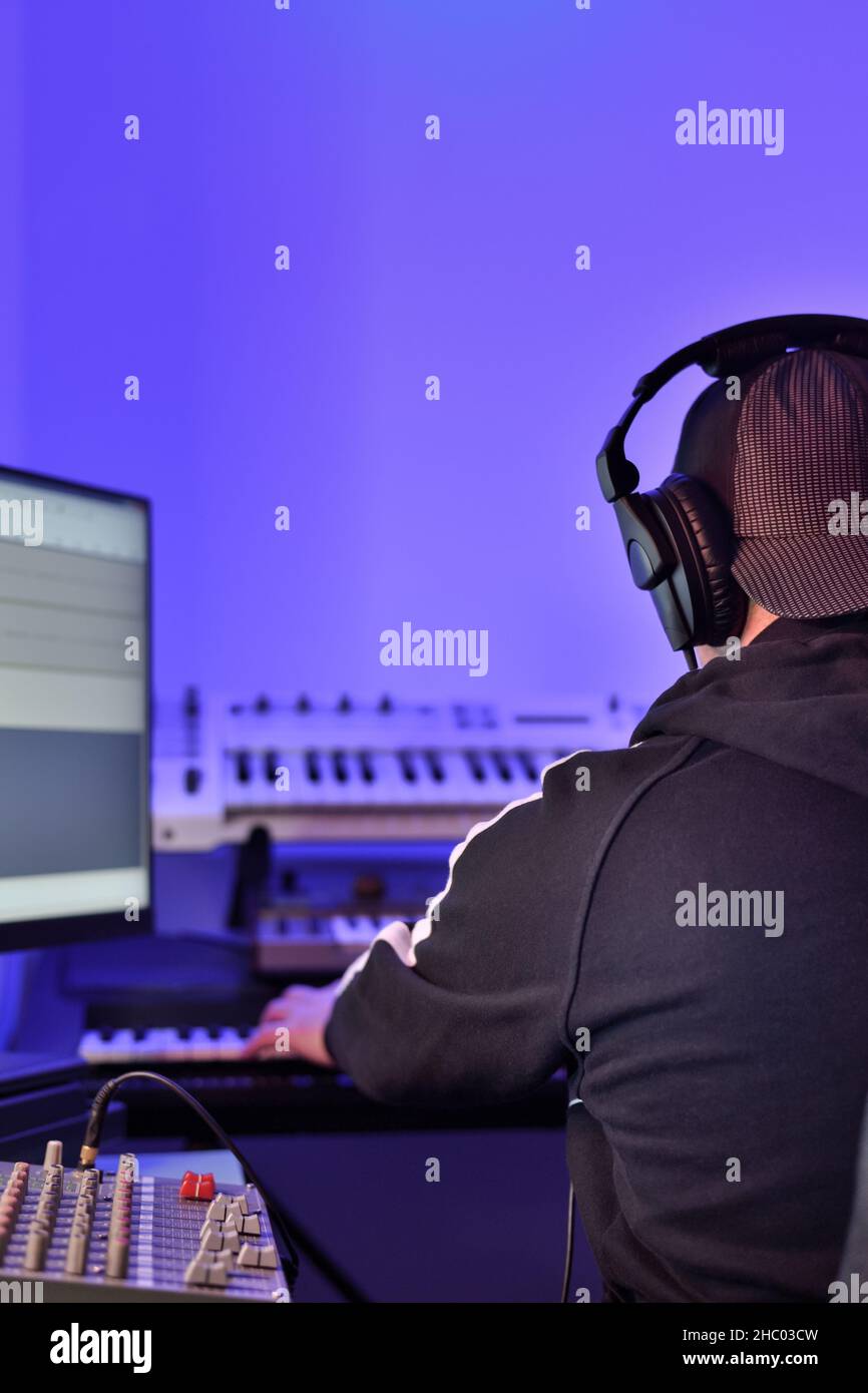 Musiker, Produzent mit Kopfhörern, der im Studio an der Erstellung und Aufnahme elektronischer Musik arbeitet. Stockfoto
