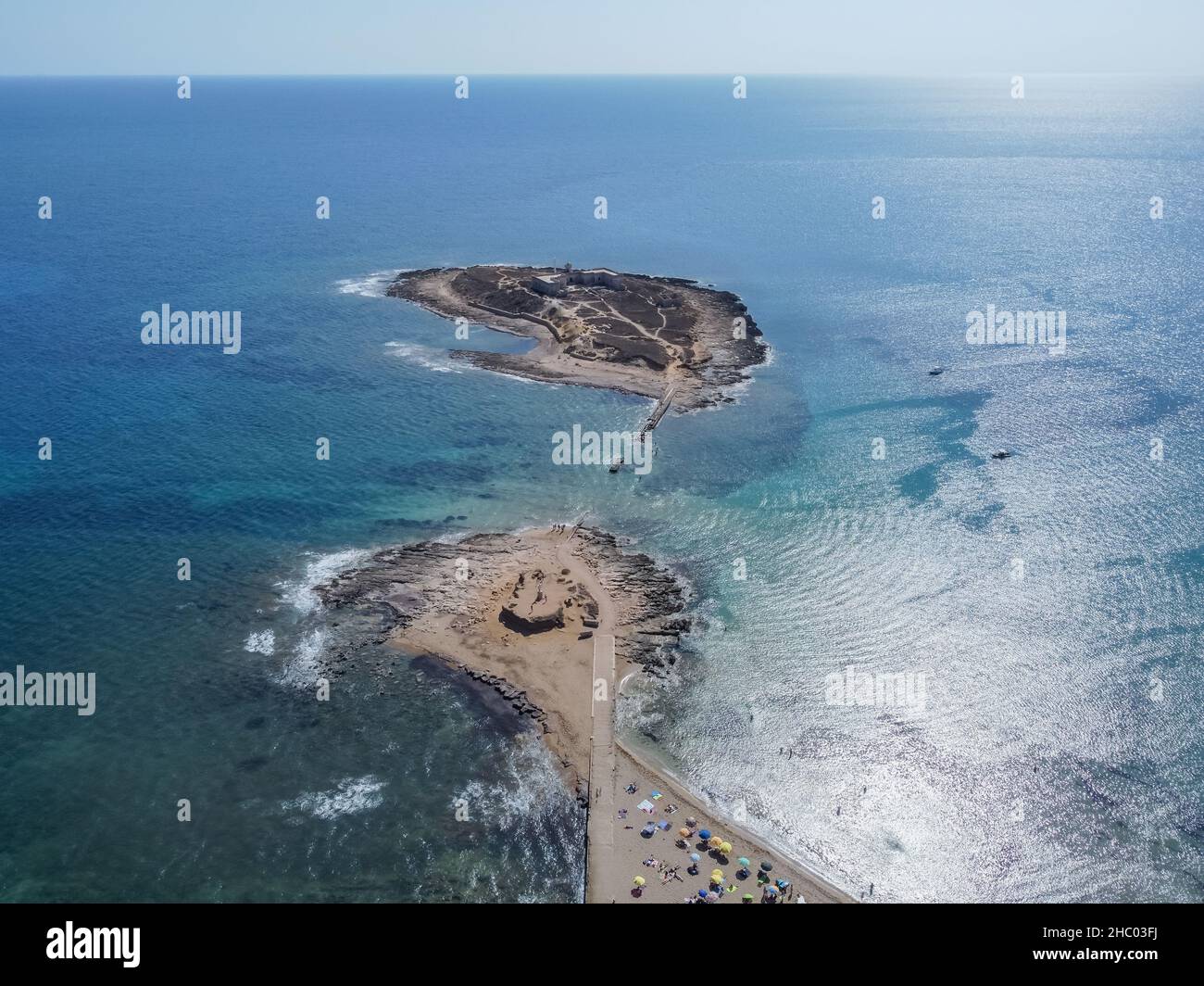 Luftdrohnenansicht der Insel und des Strandes von Isola delle Correnti. Leuchtturm umgeben von klarem türkisfarbenem Meerwasser in Portopalo di capo Passero, Sizilien Stockfoto