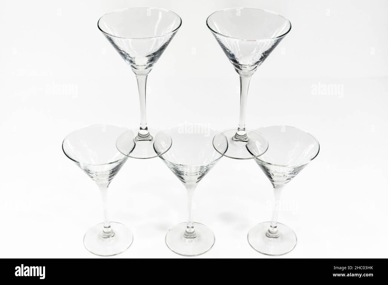 Leere martini-Cocktailgläser stehen auf weißem Hintergrund übereinander Stockfoto