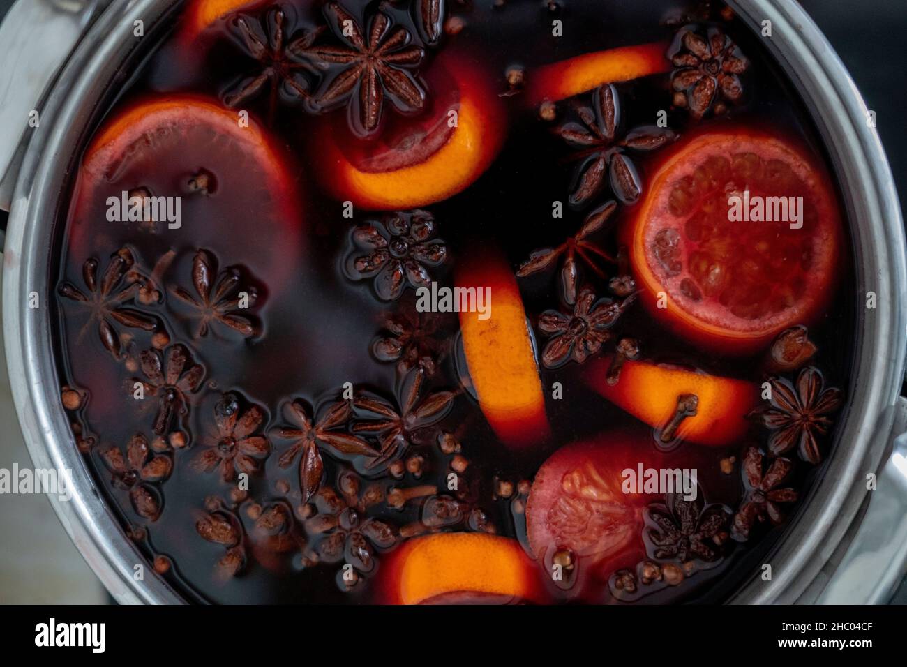Heißer Gluhwein oder Glühwein in einem Kessel mit Gewürzen und Orangenscheiben Draufsicht. Deutscher und Schweizer Traditionsgetränk im Herbst und Winter Stockfotografie