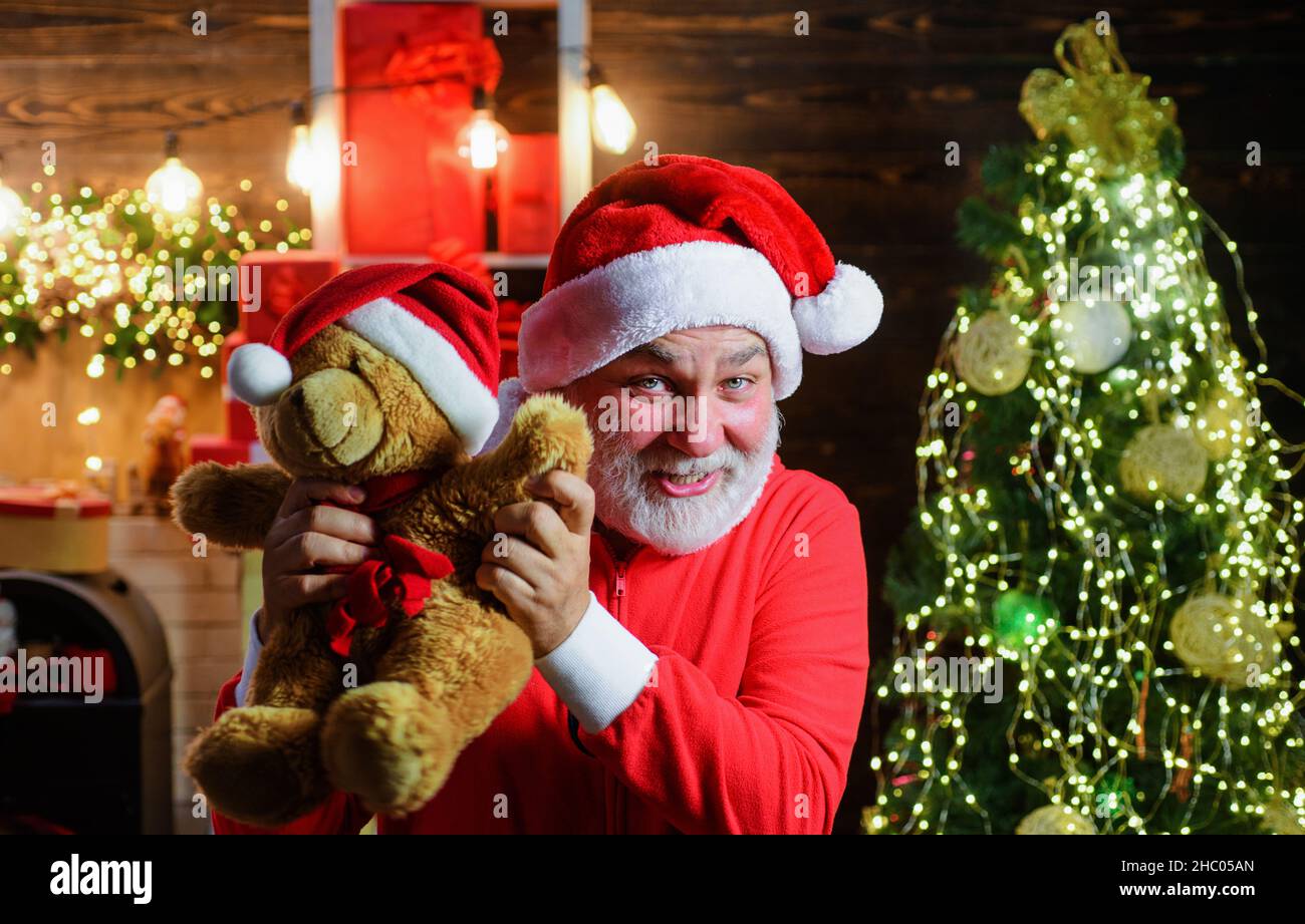 Weihnachtsferien. Weihnachtsmann mit Teddybär. Bärtiger Mann im Weihnachtsmann Kostüm mit Plüschspielzeug. Neues Jahr. Stockfoto