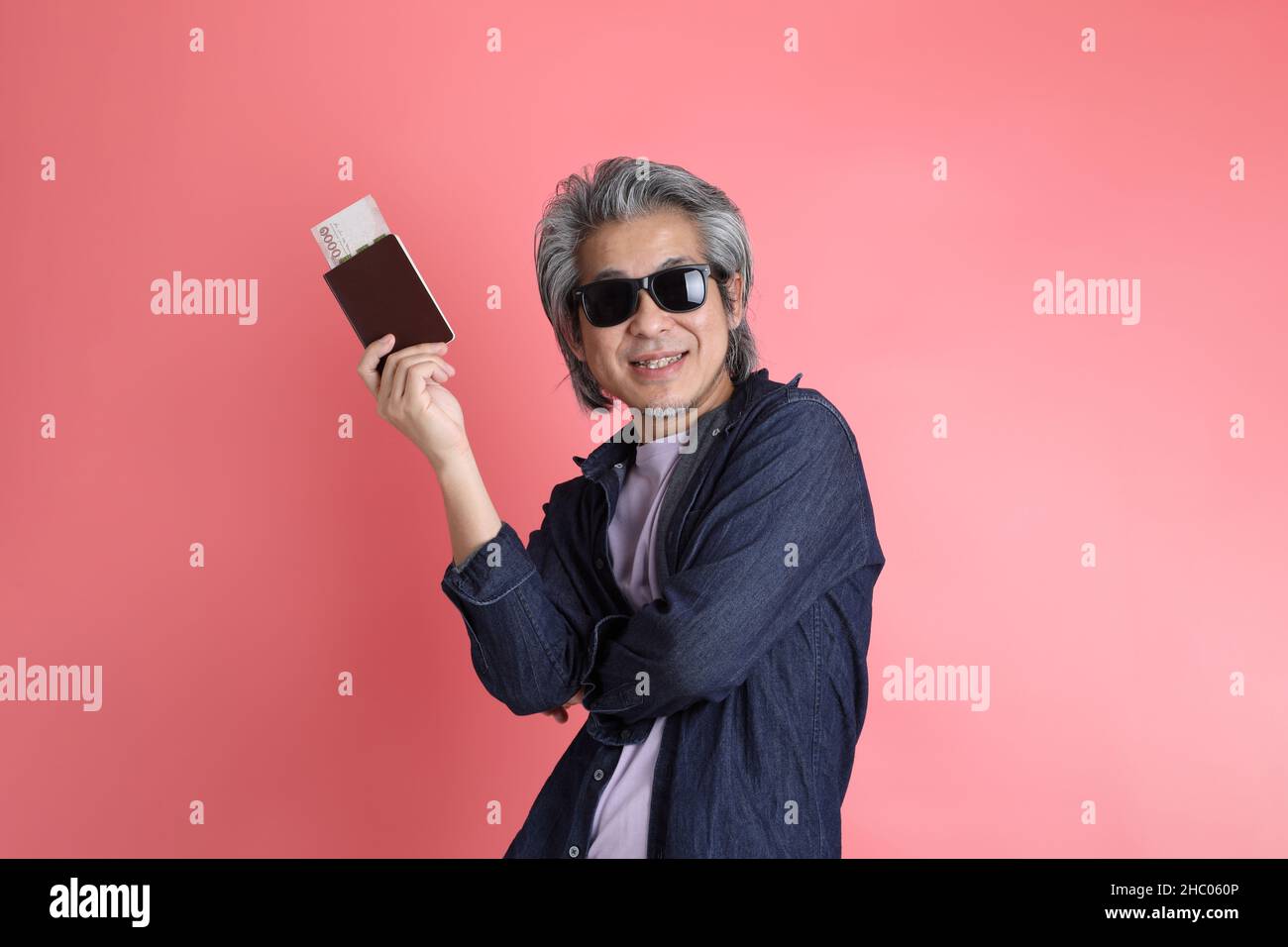 Der asiatische Mann, der auf dem rosa Hintergrund steht. Stockfoto