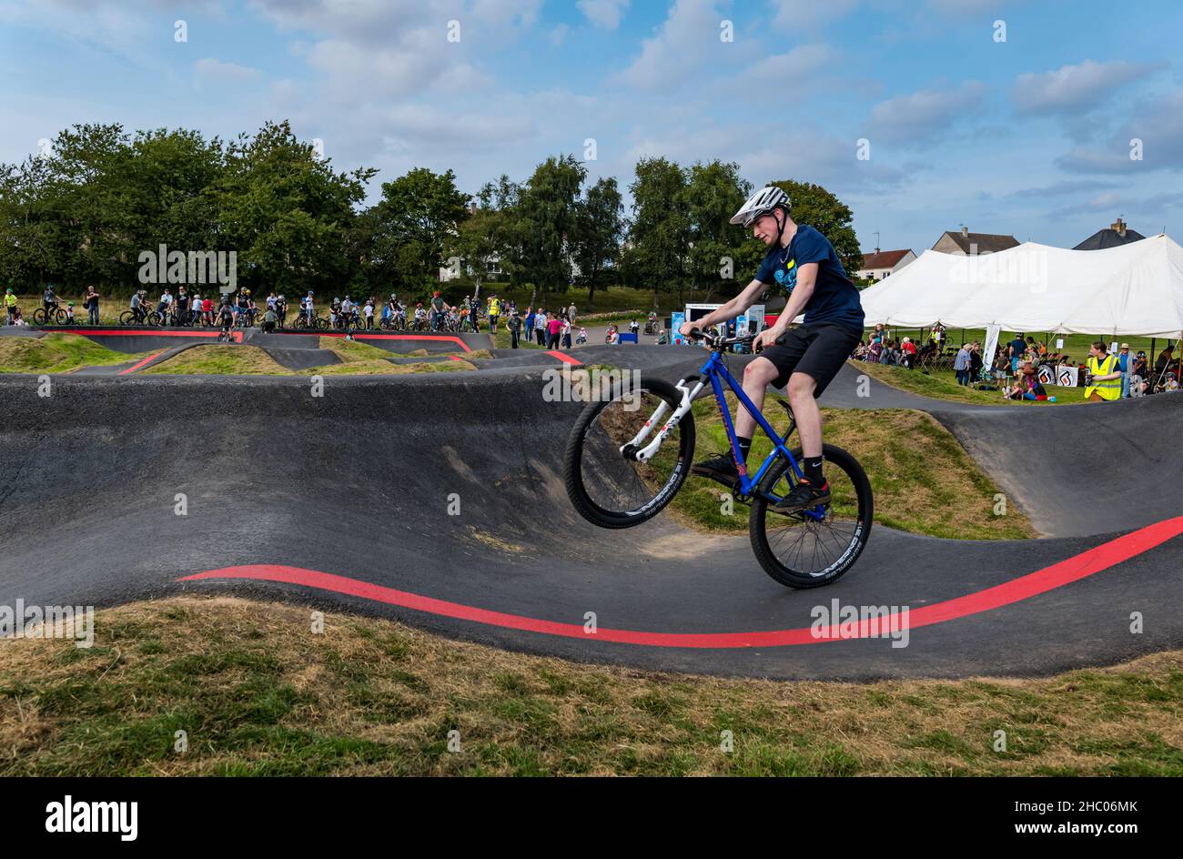 Junge, der auf einem Fahrrad auf einem Wheelie auf der BMX-Pumpstrecke von Ormiston, East Lothian, Schottland, Großbritannien, unterwegs ist Stockfoto