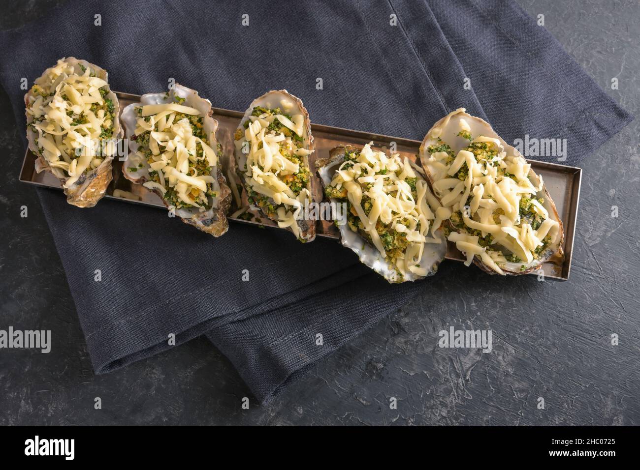 Vorbereitete Austern mit Kräuterkruste und Käse, bereit zum Backen im Ofen, dunkelgrauer Schieferhintergrund, Kopierraum, Hochwinkelansicht von oben, ausgewählt Stockfoto