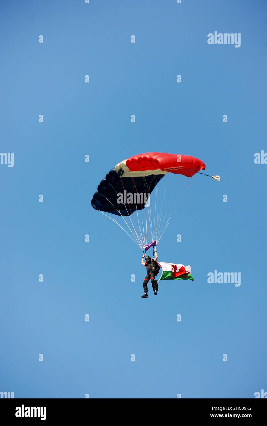 Builth Wells, Wales - Juli 2017: Fallschirmspringer mit Fallschirm, der nach einem Sprung landen wird. Die Welsh Flag fliegt von seinem Jumpsuit Stockfoto