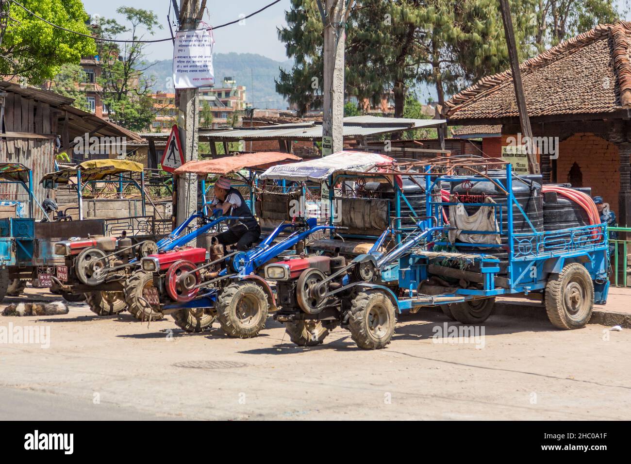 In Kathmandu, Nepal, sitzt ein Fahrer in einem der zweirädrigen Traktoren mit Wassertanks auf Anhängern. Stockfoto