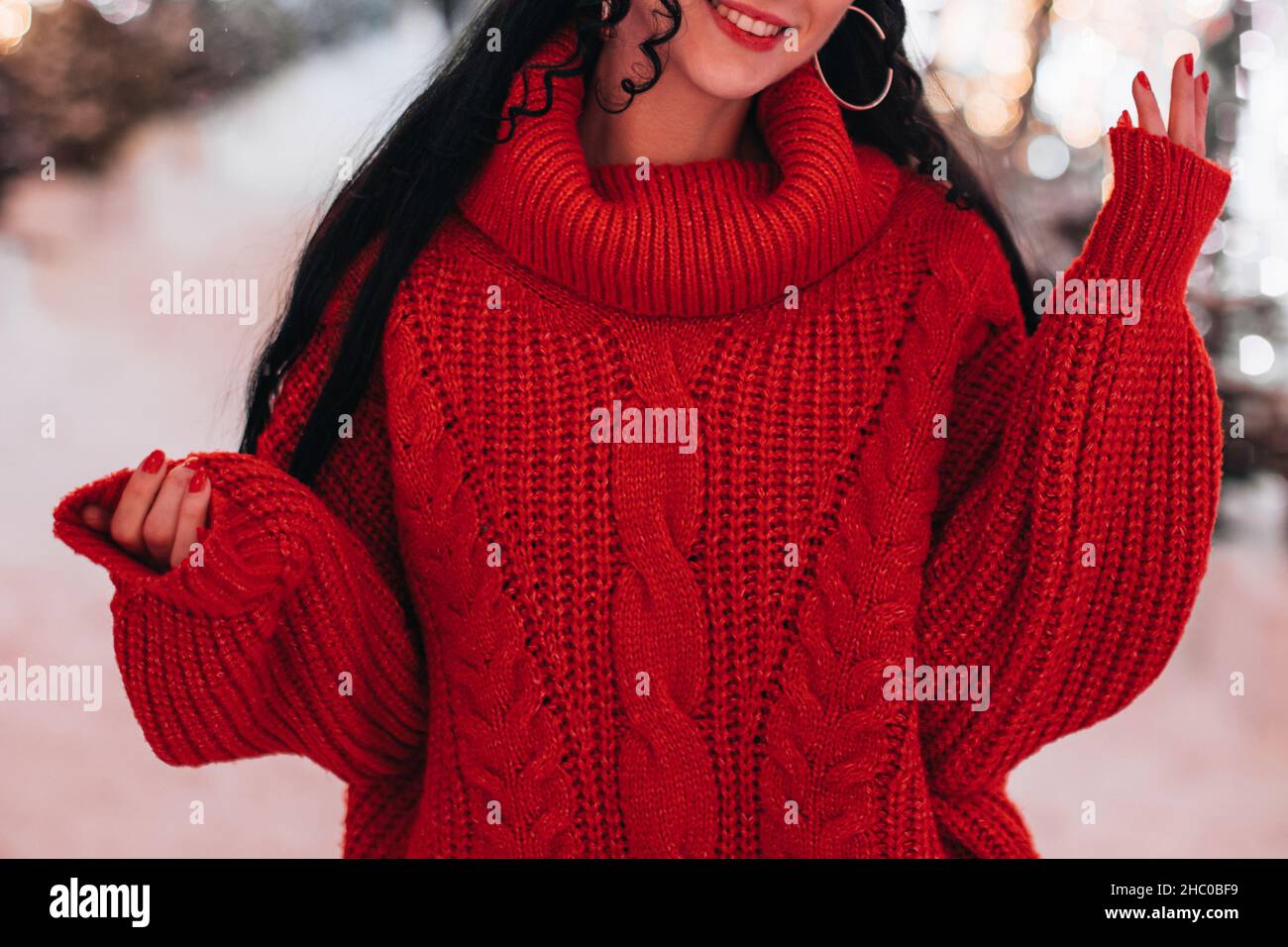 Junge Brünette Frau in einem gestrickten gemütlichen Winterpullover und roten Lippen. Weihnachts- und Neujahrsstimmung Stockfoto