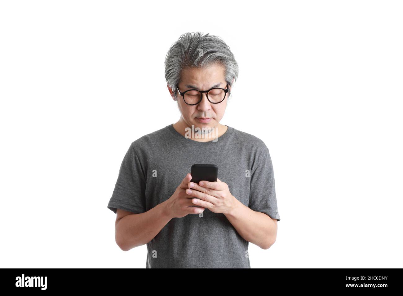 Der ältere asiatische Mann mit Smartphone auf dem weißen Hintergrund. Stockfoto