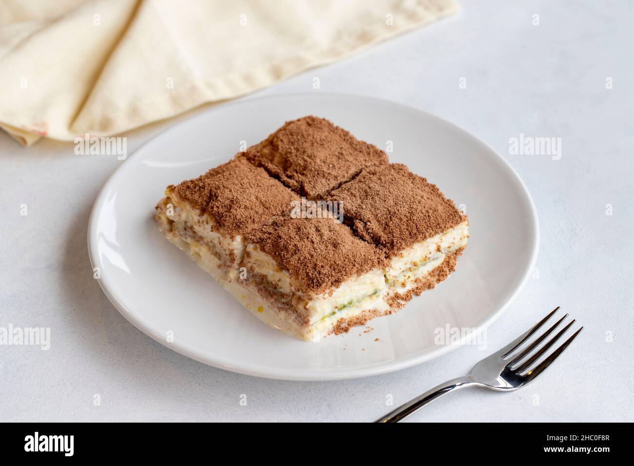 Kaltes Baklava auf weißem Hintergrund. Türkische süße Dessert-Konzept. Teller mit geschnittenem Waldobstkuchen. Platte aus kalter Milch Baklava. Mediterrane Bäckerei Stockfoto