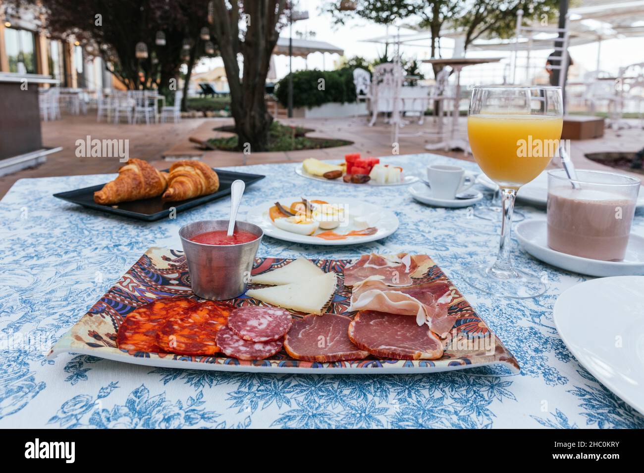 Kontinentales Frühstück auf der Terrasse mit Orangensaft, Obst, Kakao, Kaffee, Gebäck, Aufschnitt, Tomaten usw. Stockfoto