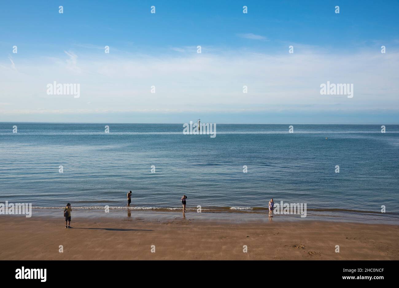 Vier Menschen stehen bei Ebbe an einem Sandstrand in Margate in Kent Stockfoto