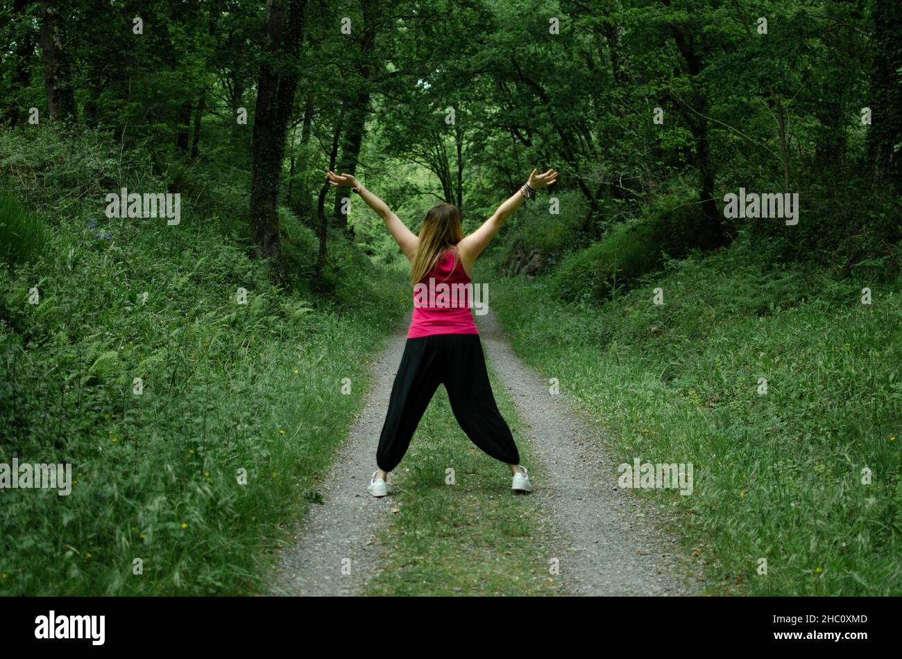 Blondine geht durch den Wald, trägt ein türkisfarbenes T-Shirt. Das Mädchen tanzt Stockfoto