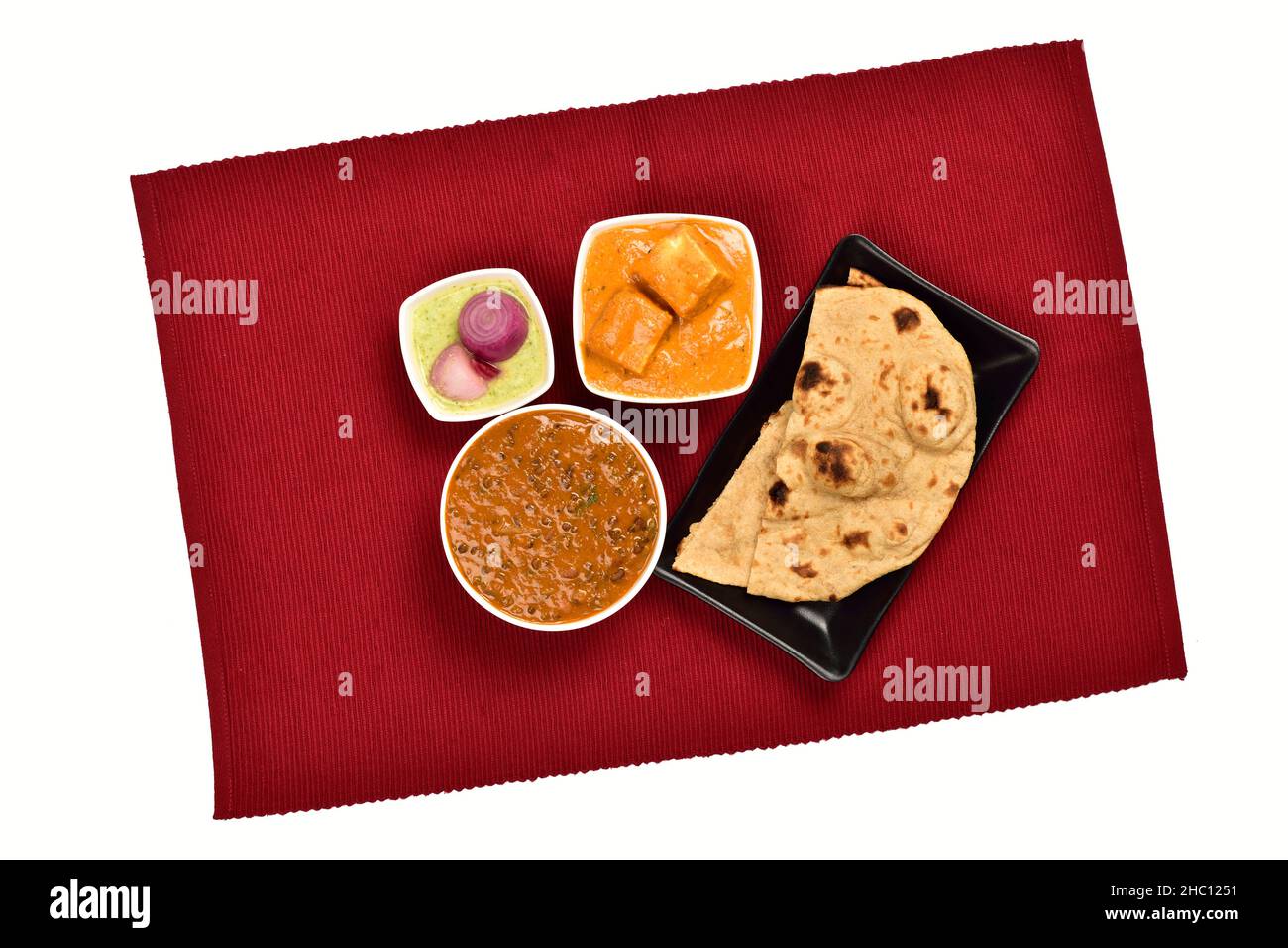 Draufsicht auf Shahi Paneer und Dal Makhani in Schüssel serviert mit Chapati und Chutney Pickle Onion auf Tischset isoliert auf weißem Hintergrund Stockfoto