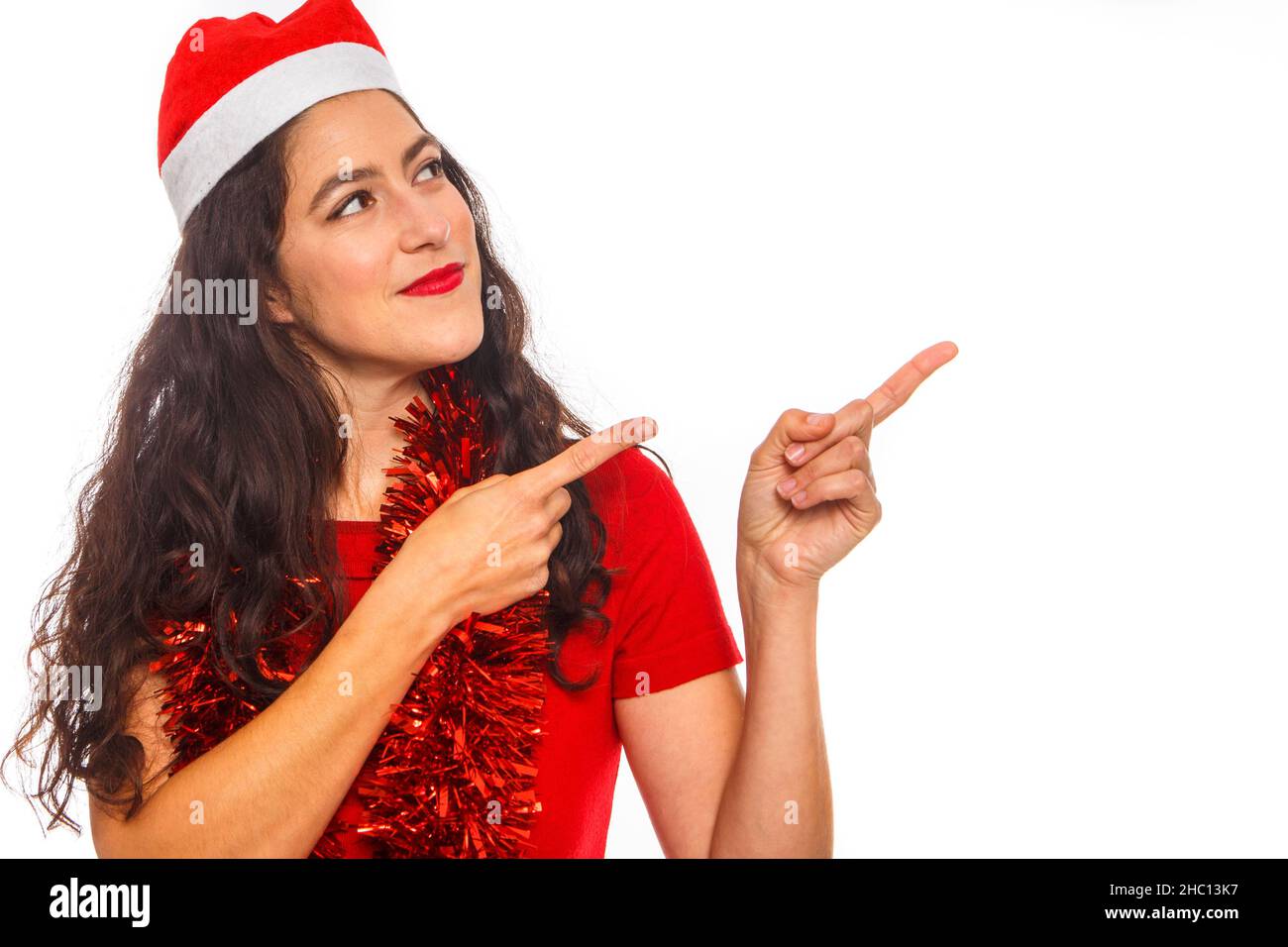 Reife Frau im Mantel und Weihnachtshut zeigt Finger bis Raum isoliert auf weißem Hintergrund, Studio-Porträt zu imitieren. Happy New Year Konzept Stockfoto