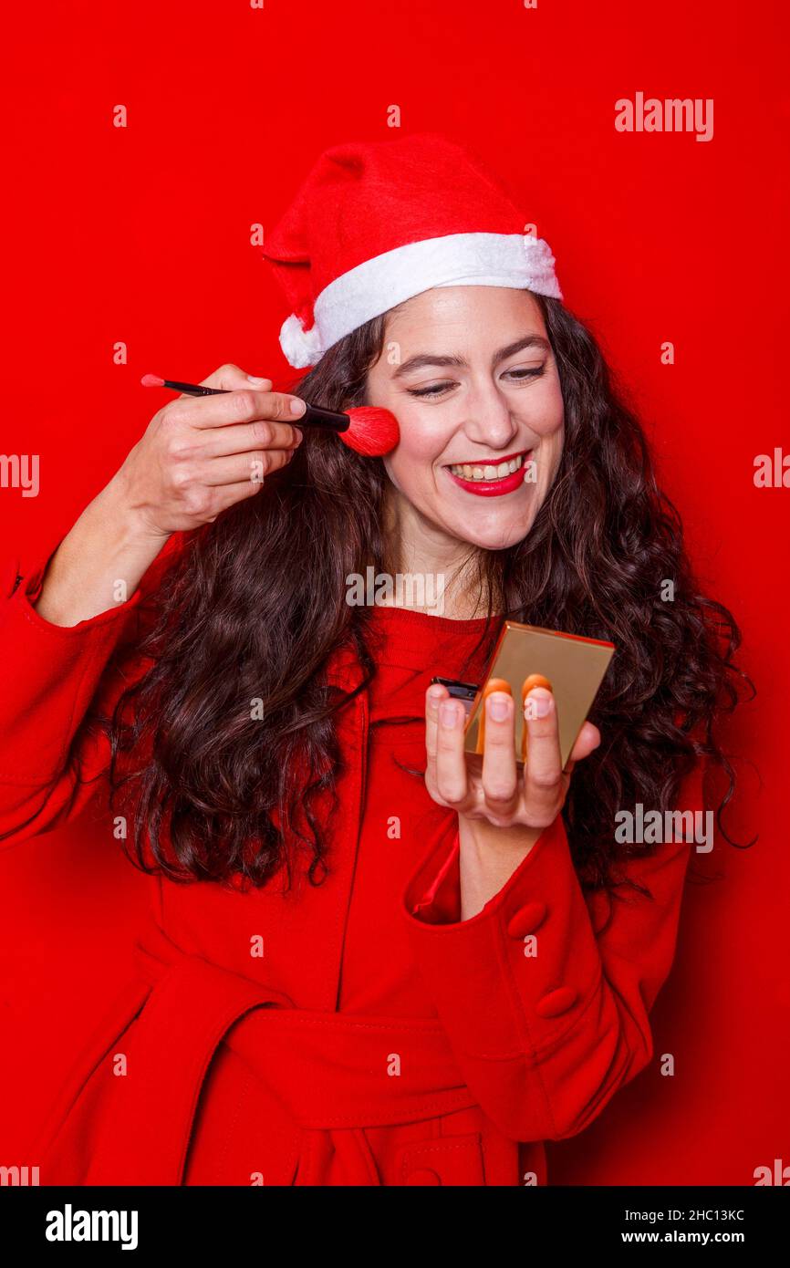 Fröhliche Frau in Santa Hut auf Make-up mit roten Pinsel Stockfoto