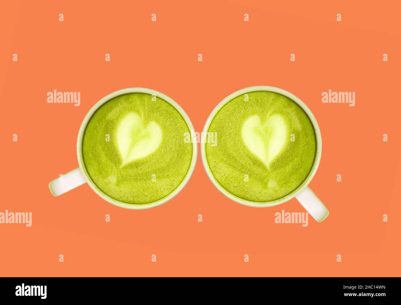 Grünes Tee von Matcha mit herzförmiger Latte Art vor orangefarbenem Hintergrund Stockfoto