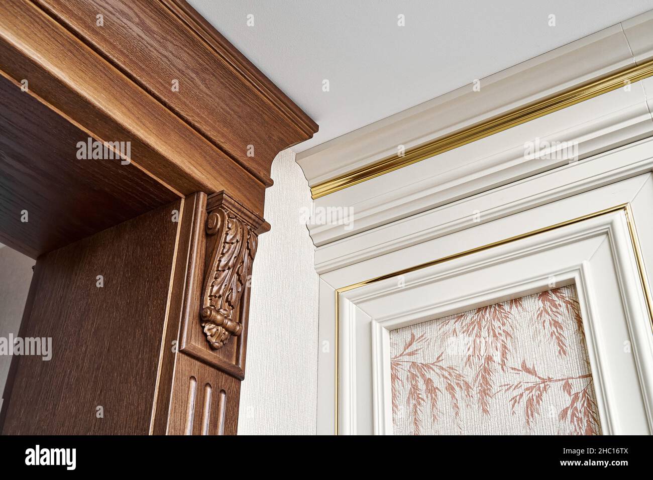 Verzierte hölzerne Tür mit geschnitzten Möbelhalterungen und geriffelten Paneele und Vintage Wandpaneel mit goldenen Zierleisten in klassischem Stil Nahaufnahme Stockfoto