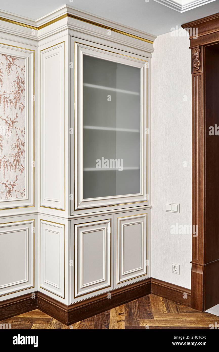 Vintage Vitrine mit Stuckleisten und Glastür im klassischen Stil in der Nähe dekorierter Holztür im hellen, geräumigen Zimmer der Hütte Stockfoto