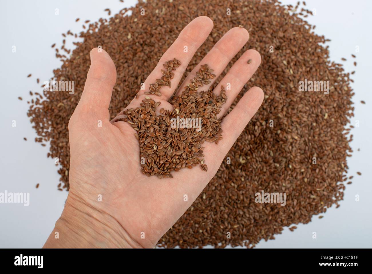 Hand hält braune Leinsamen. Nahaufnahme, Draufsicht. Stockfoto