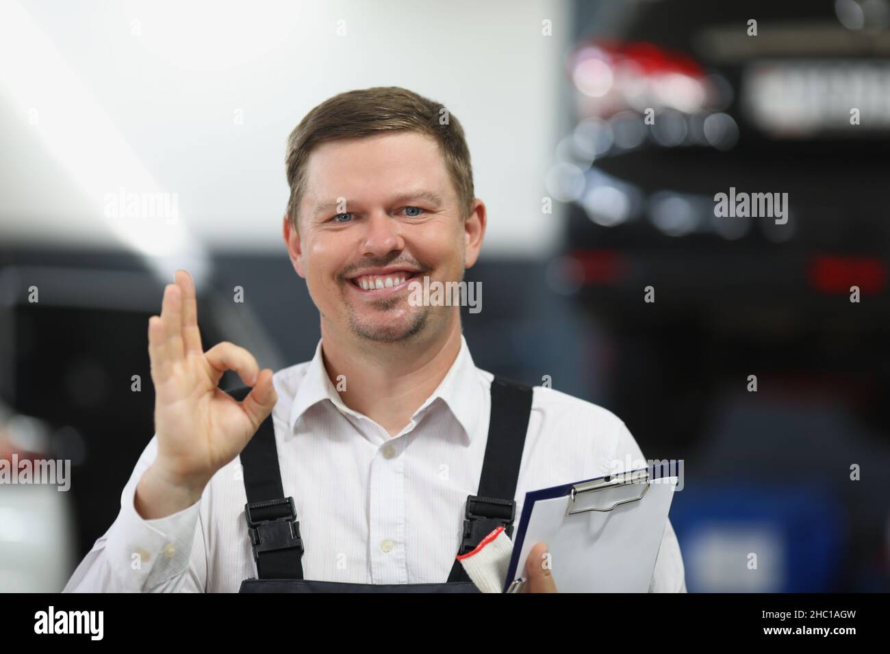 Der Mitarbeiter des Reparaturdienstes zeigt eine gute Geste mit der Hand und lächelt Stockfoto