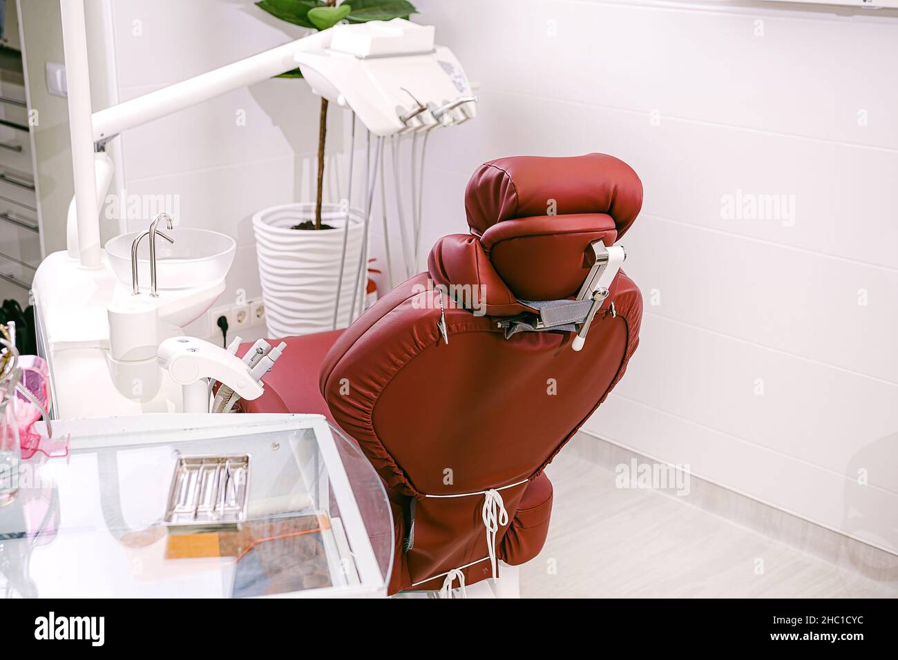 Foto eines Stomatologieschranks mit einem Stuhl, zahnärztlichen Instrumenten auf dem Arbeitstisch und einem Blumentopf. Stockfoto