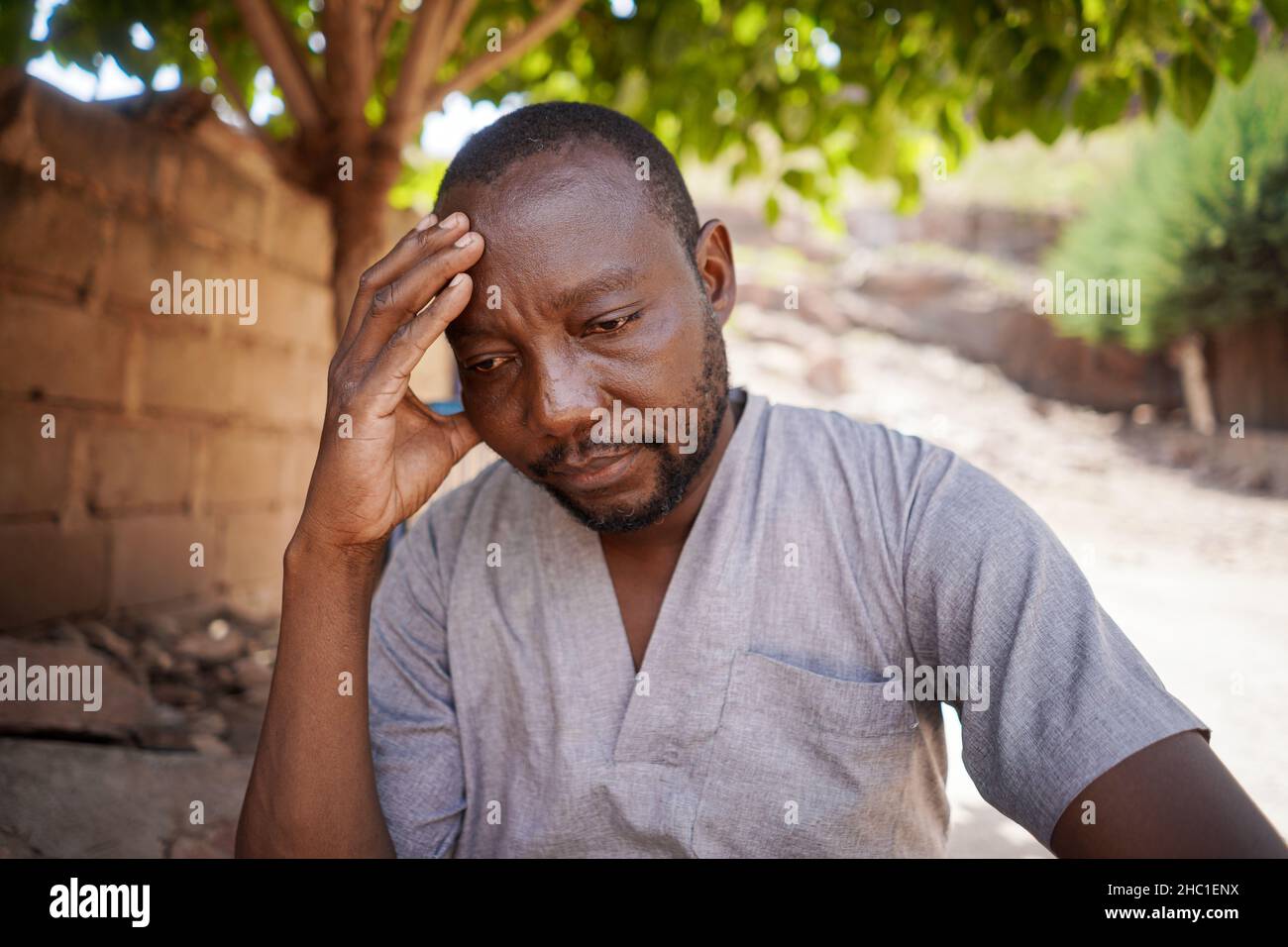 Beunruhigte schwarze afrikanische Dorfbewohner, die über seine täglichen Lebensprobleme nachdenken Stockfoto