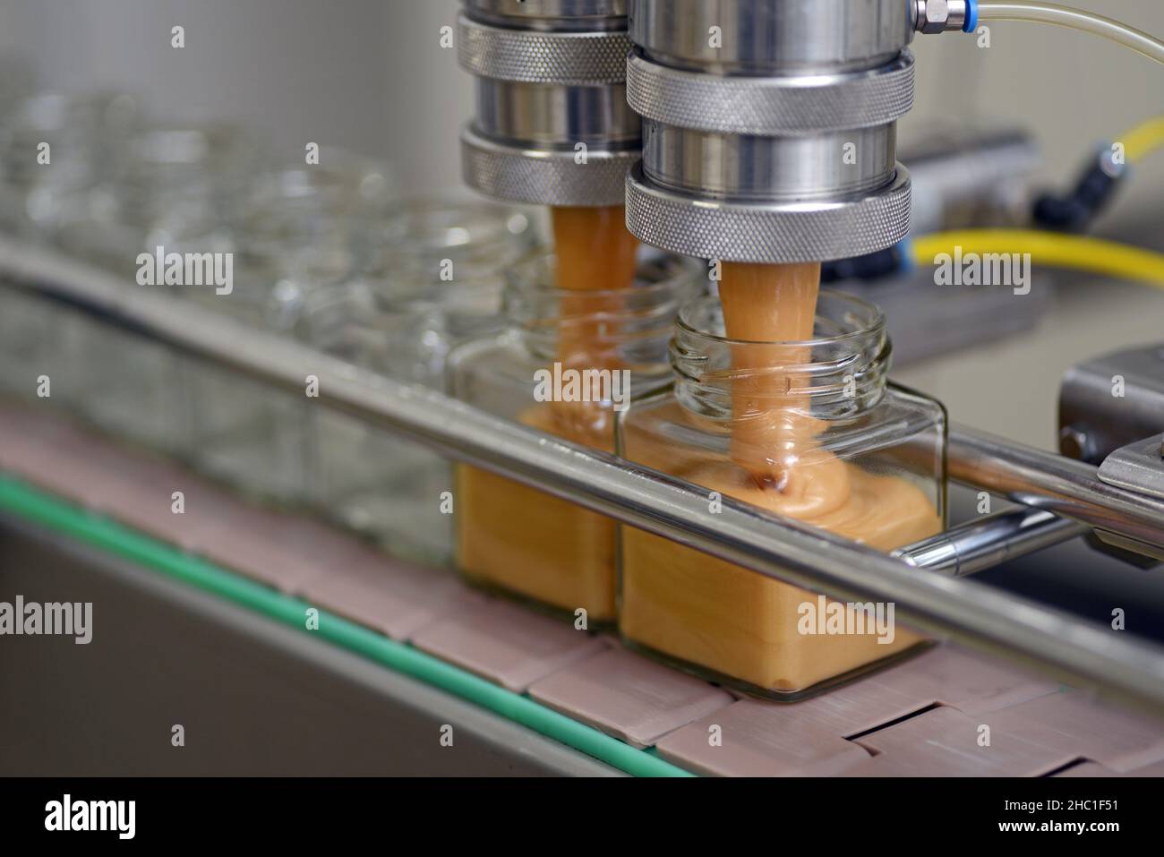 Gläser mit Rahmhonig in einer Verpackungslinie in einer kommerziellen Honigfabrik Stockfoto