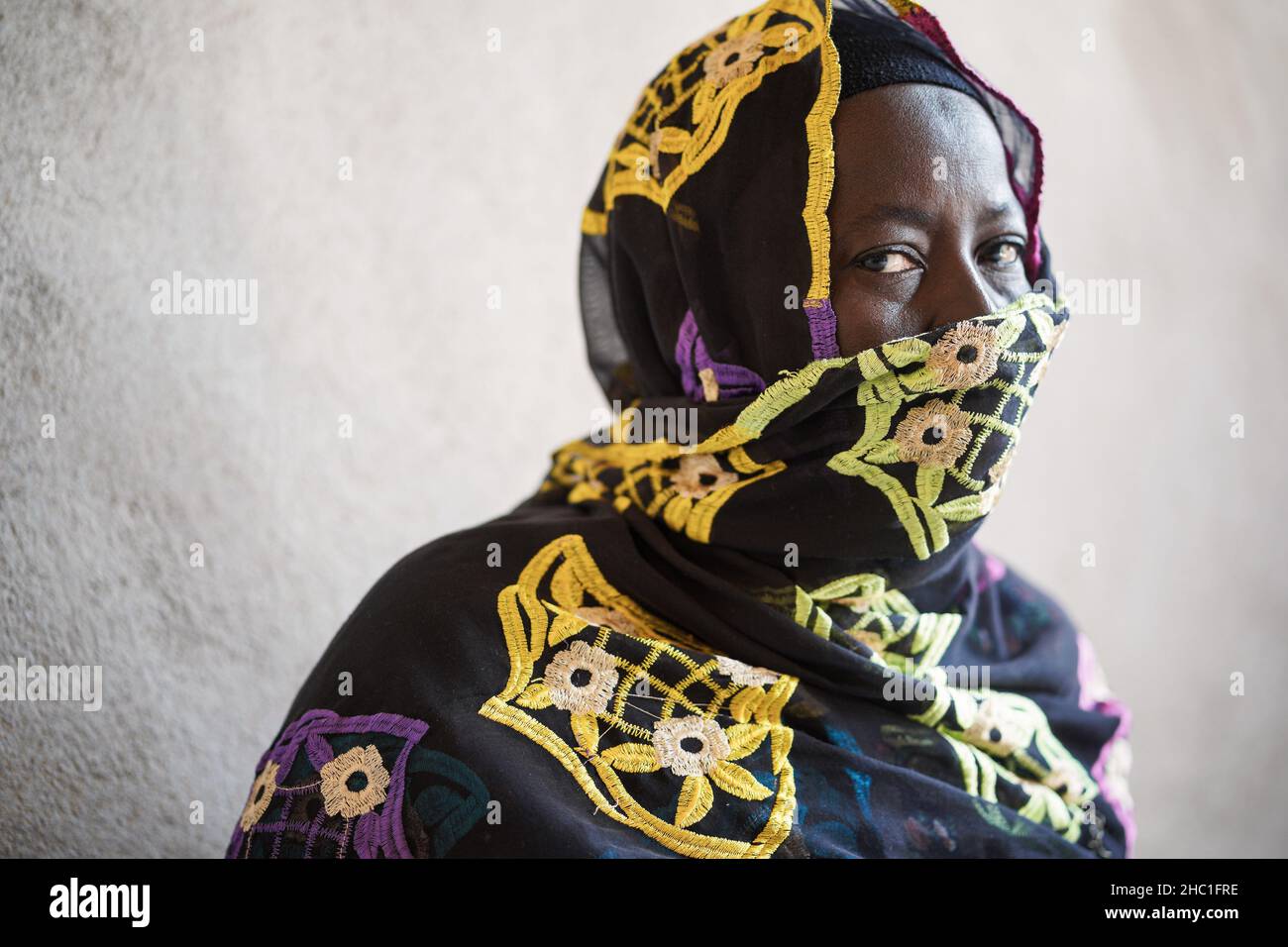 Ältere schwarze afrikanerin, deren Gesicht von einem Schleier bedeckt ist und traurig auf die Kamera schaut; Konzept der Bevölkerungsalterung Stockfoto