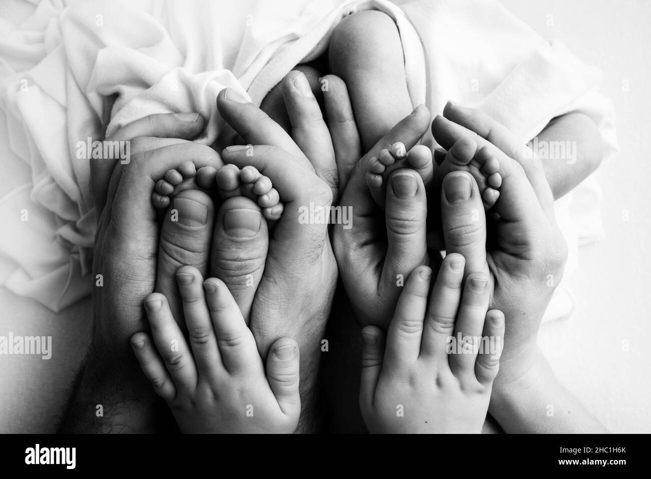 Füße neugeborener Zwillinge. Eltern, Vater Mutter älterer Bruder halten neugeborene Zwillinge Stockfoto