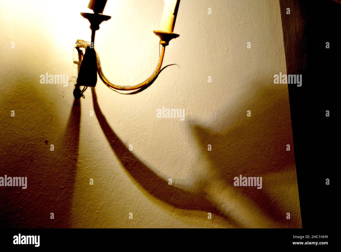 Es war einmal – lang gestreckte Schatten, die von einer Lampe mit Kerzen in einem alten Palast erzeugt werden - Sansepolcro (Italien) Stockfoto