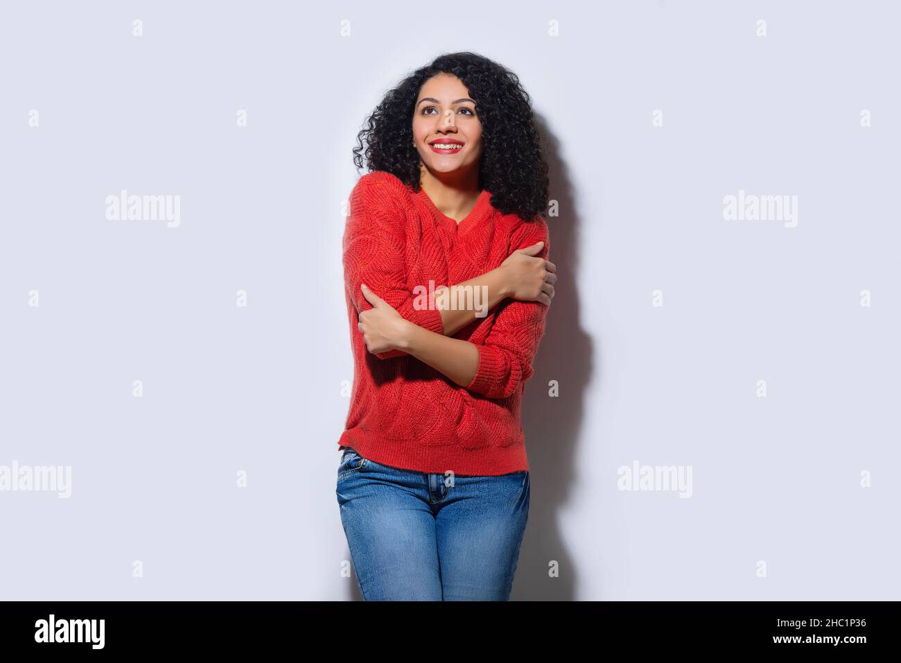 Schöne Frau, die mit gekreuzten Händen steht und nach oben schaut Stockfoto