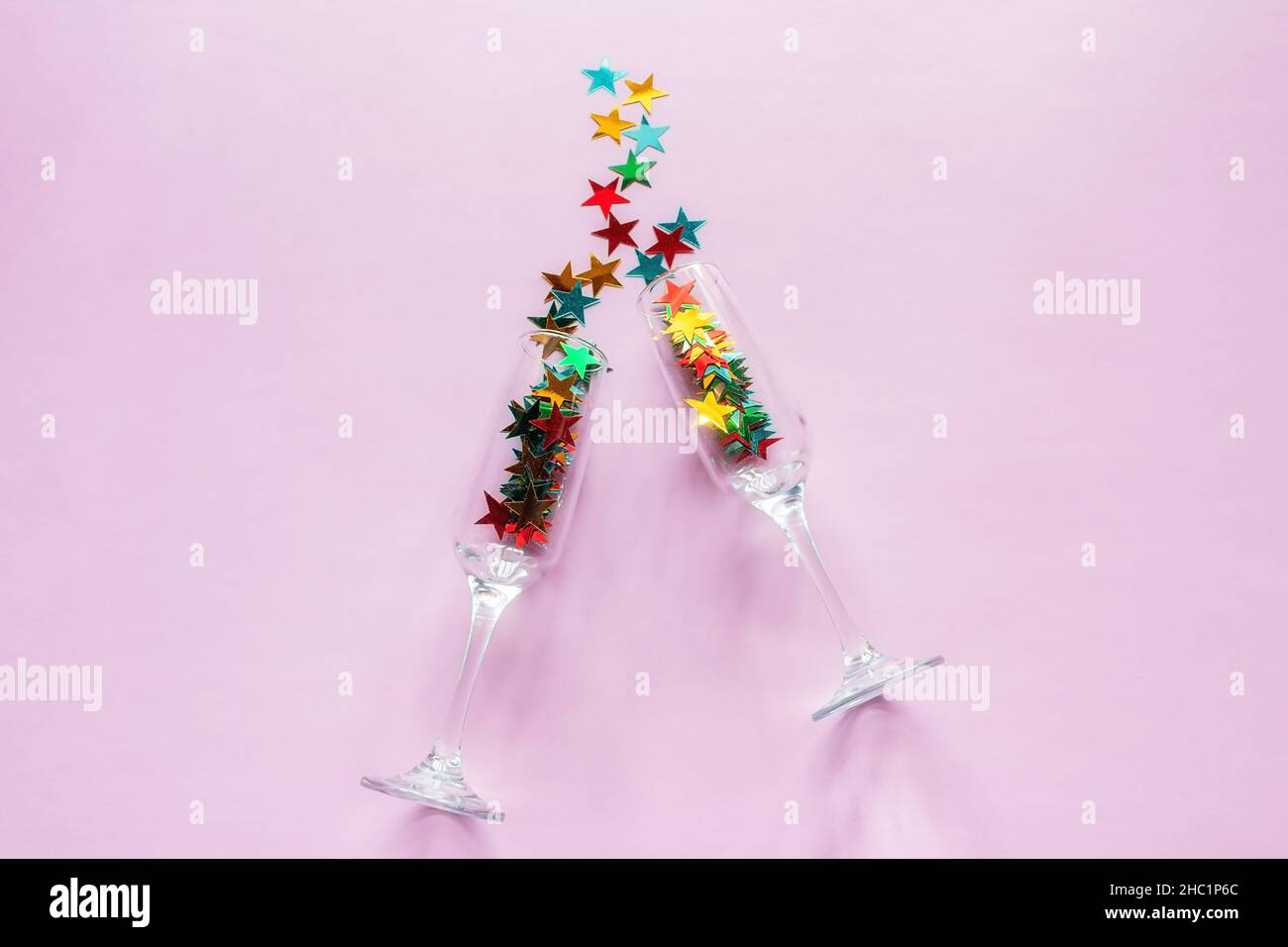Sektgläser und bunte Konfetti Happy New Year Konzept auf rosa Hintergrund Stockfoto