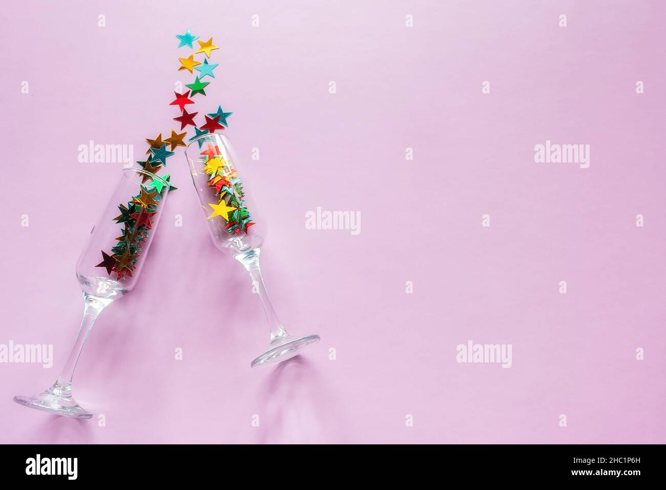 Champagner Gläser und Konfetti Konzept fröhliche weihnachten Neujahr auf rosa Hintergrund mit Platz für Text Stockfoto