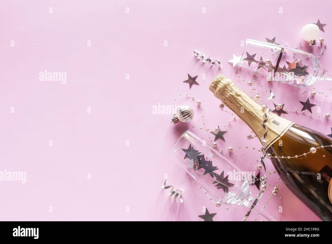 Champagner und Konfetti auf rosa Hintergrund mit Platz für Text fröhlich weihnachten neues Jahr Stockfoto