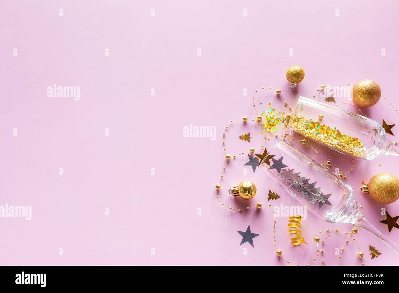 Gläser und Konfetti auf rosa Hintergrund mit Platz für Text fröhlich weihnachten Neujahr Urlaub Stockfoto