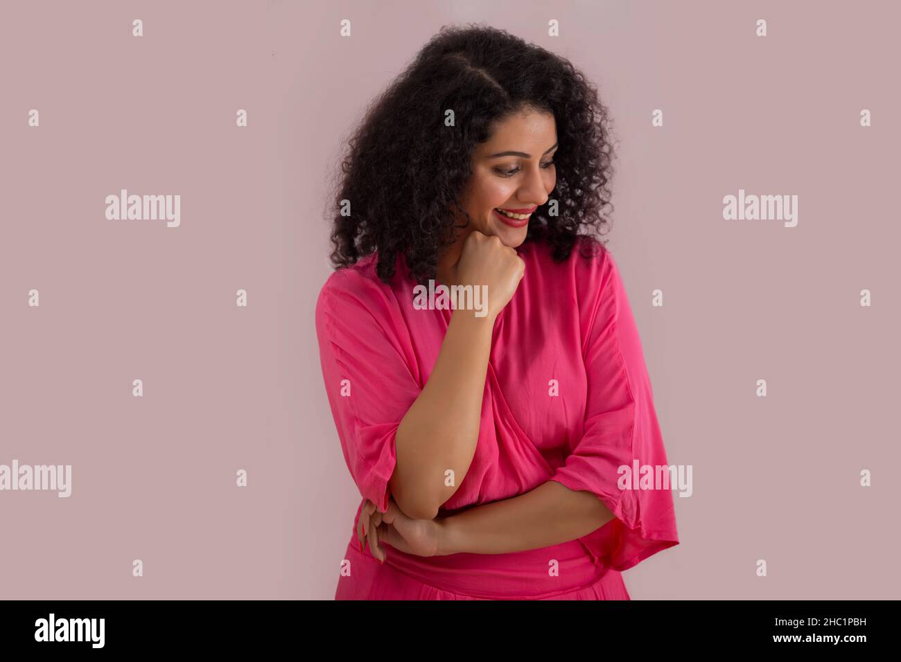 Schöne Frau in rosa Outfit Blick nach unten mit der Hand auf dem Kinn Stockfoto